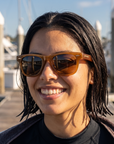 Woman, 25, wearing Peppers Chilmark sunglasses in Caramel Frame with Brown Lens, on an empty harbour dock after a dive