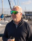 Man, 54, wearing Peppers Cool Driver sunglasses in Matte Grey Frame with Green Revo Lens, on a marina walkway