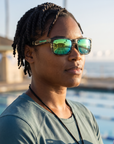 Woman, 34, wearing Peppers Daybreak sunglasses in Shiny Green Striped Tort Frame with Green Mirror Lens, on an ocean-side pool deck