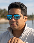 Man, 40, wearing Peppers Defender sunglasses in Matte Grey Frame with Blue Revo Lens, at a shallow inlet