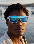 Man, 27, wearing Peppers Enzo sunglasses in Shiny White Frame with Blue Diamond Mirror Lens, at a calm bay beach