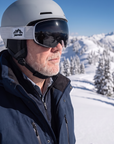 Man, 54, wearing a ski helmet and Peppers Glade Runner Pro goggles in Shiny White with Smoke, on a groomed run