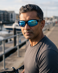 Man, 43, wearing Peppers Grand Slam sunglasses in Crystal Blue Frame with Blue Revo Lens, on a waterfront bike path
