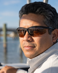 Man, 40, wearing Peppers Ricochet sunglasses in Matte Black Frame with Brown Lens, at a shallow inlet