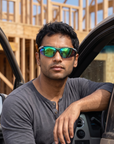 Man, 29, wearing Peppers Ricochet sunglasses in Matte Dark Green / Silver Frame with Green Diamond Mirror Lens, at a house-framing jobsite