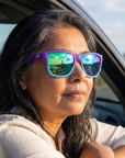 Woman, 48, wearing Peppers Sailfish sunglasses in Matte Transparent Purple Gradient Blue Green Diamond Mirror, on a seaside road