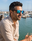 Man, 41, wearing Peppers Seawitch sunglasses in Matte Black to Tort Frame with Blue Revo Lens, on a waterfront yacht-club terrace