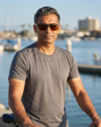 Man, 43, wearing Peppers Seawitch sunglasses in Matte Black To Tortoise Frame with Brown Lens, on a waterfront bike path along a harbour
