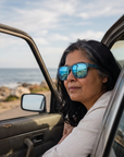 Woman, 48, wearing Peppers Sweetwater sunglasses in Dove Grey Frame with Light Blue Mirror Lens, on a seaside road