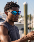 Man, 26, wearing Peppers Three Wood sunglasses in Matte Black Frame with Blue Revo PC Lens, at a busy marina