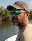 Man, 44, wearing Peppers Anchor sunglasses in Shiny Crystal Grey Frame with Smoke Emerald Green Mirror Lens, on a flats skiff