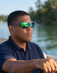 Man, 49, wearing Peppers Big Kahuna sunglasses in Dark Grey Frame with Green Diamond Mirror Lens, on a calm lake