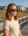 Woman, 31, wearing Peppers Cool Breeze sunglasses in Shiny Black Fade to Shiny Tortoise with Smoke, on a beach boardwalk