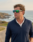Man, 34, wearing Peppers Cutthroat sunglasses in Matte Grey Frame with Emerald Green Mirror Lens, on a coastal golf course above the ocean
