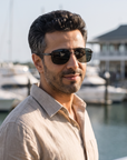Man, 41, wearing Peppers Defender sunglasses in Matte Black Frame with Smoke Lens, on a waterfront yacht-club terrace