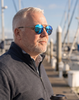 Man, 54, wearing Peppers Django sunglasses in Shiny Dark Antique Silver Frame with Blue Mirror Lens, on a marina walkway