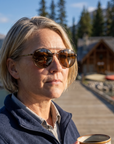 Woman, 43, wearing Peppers Django sunglasses in Shiny Dark Antique Brown Frame with Brown Lens, at a mountain-lake lodge dock