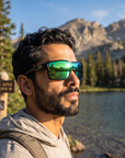 Man, 35, wearing Peppers Enzo sunglasses in Smoke Crystal Frame with Green Diamond Mirror Lens, at an alpine lake trailhead
