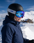 Woman, 43, wearing Peppers Glade Runner Pro goggles in Matte Black with Blue Revo, on a snowy ridge