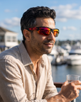 Man, 41, wearing Peppers Grand Slam sunglasses in Matte Black Frame with Red Revo Lens, on a waterfront yacht-club terrace