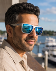 Man, 41, wearing Peppers Hammerhead sunglasses in Metallic Silver Frame with Blue Revo Mirror Lens, on a waterfront yacht-club terrace