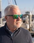 Man, 54, wearing Peppers Hammerhead sunglasses in Matte Dark Grey Frame with Green Revo Lens, on a marina walkway