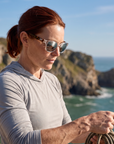 Woman, 35, wearing Peppers Mermaid sunglasses in Shiny Crystal Frame / Tort Temples with Silver Mirror Lens, on a sea cliff above the water