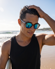 Man, 24, wearing Peppers Mermaid sunglasses in Shiny Honey Tort Frame with Blue Diamond Mirror Lens, on a surf beach after a session