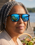 Woman, 59, wearing Peppers Milano sunglasses in Shiny Black Frame with Blue Mirror Lens, on a lakeside garden dock
