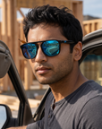 Man, 29, wearing Peppers Milano sunglasses in Shiny Black Frame with Blue Mirror Lens, at a house-framing jobsite