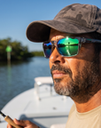 Man, 44, wearing Peppers Mountain Madness sunglasses in Shiny Crystal Grey Frame with Green Diamond Mirror Lens, on a flats skiff