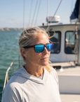 Woman, 45, wearing Peppers Sweetwater sunglasses in Shiny Demi Frame with Blue Mirror Lens, on open water