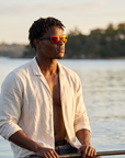 Man, 27, wearing Peppers Sweetwater sunglasses in Matte Black Frame with Red Mirror Lens, on a glassy bay