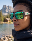 Woman, 26, wearing Peppers Whaler sunglasses in Dark Gunmetal Frame with Green Diamond Mirror Lens, at a mountain-lake shore